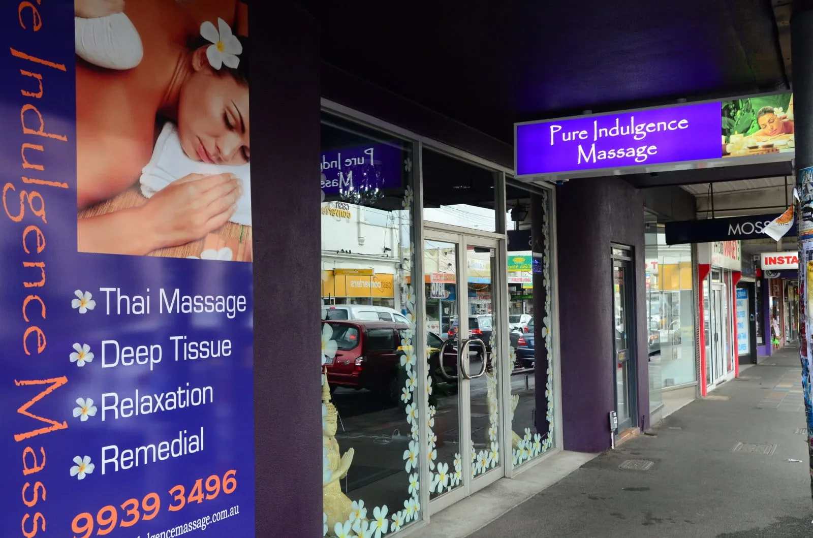 High Street shopfront — purple Pure Indulgence Massage facade with lit signage and service banners